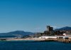 Coastal town with historic tower overlooking the sea.