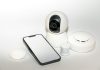 Un accesoriu AI de dimensiune similară cu un puck promite să revoluționeze casa a smart phone sitting next to a security camera