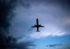 a plane flying in the sky with a cloudy background