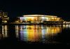 a building is lit up at night by the water