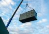 Crane lifting a large shipping container against the sky