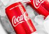 Two red Coca-Cola cans covered in condensation resting on a bed of ice